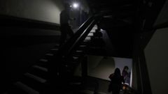 Dos personas transitan por la escalera de un edificio a oscuras de la capital venezolana