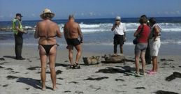 Ba�istas en la playa de Arealonga observando con curiosidad los fardos que arroj� el mar. 