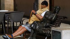 Un hombre sentado al sol con su mascarilla en la Plaza del Font�n en Oviedo