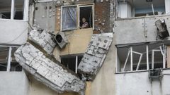Un hombre se asoma a la ventana de un edificio alcanzado por el bombardeo ruso en Kiev