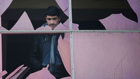 Un joven mira a trav�s de una ventana rota en Kabul, despu�s de un atentado
