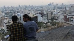 Dos iranes, uno con una camiseta con un lema estadounidense, observan Tehern tras el bombardeo a la televisin estatal.