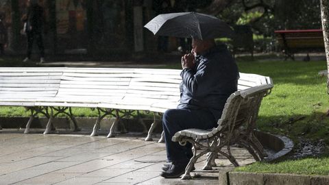 Un hombre se cubre de la lluvia en un banco del Parque de la Alameda, en Santiago.