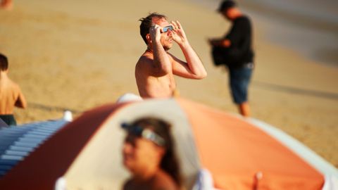 Un hombre mira al eclipse en la playa de Doni�os.