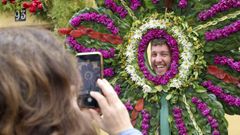 Una persona posa en una de las estructuras florales de las Festas dos Maios de Canido.