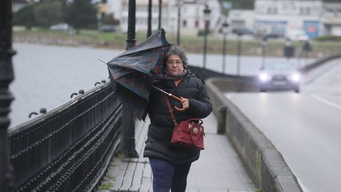 Una se�ora atraviesa con apuros debido al viento el puente viveirense de A Misericordia.