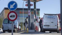 Dos trabajadores repostan sus furgonetas en una gasolinera de Santiago