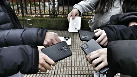 Alumnas del IES As Lagoas de Ourense sotienen sus móviles a la entrada del centro