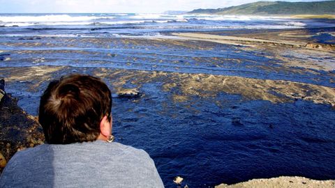 Un vecino observa el desastre ecolgico que deja la marea negra en Laxe