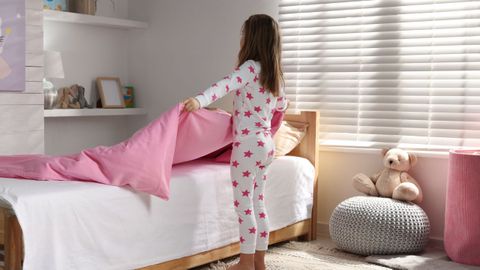 Imagen de una ni�a haciendo su cama.