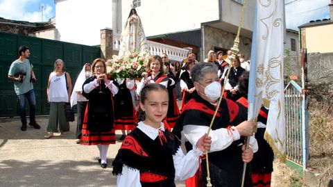 Mujeres vestidas con el traje tradicional gallego se turnan para llevar la imagen de la Virgen en procesin entre las casas de A Ermida