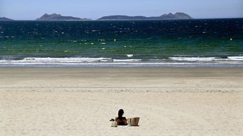 Una mujer disfruta al sol en la playa de Samil, con privilegiadas vistas a las islas C�es