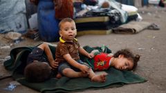 Nios palestinos descansan en el camino hacia el sur del enclave, tras ser forzados a abandonar la ciudad de Gaza. 