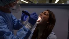 Un especialista del aeropuerto de Viena recoge una muestra de saliva de una pasajera para realizarle un test r�pido de ant�genos