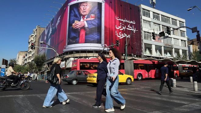 Iran&iacute;es pasan ante un gran cartel con la imagen de Trump en una avenida de Teher&aacute;n