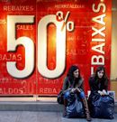 Dos mujeres delante de un cartel de rebajas.