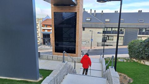 Una mujer con bastón, bajando por las escaleras al comprobar que el ascensor no funciona.