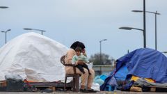 Una mujer sostiene a un beb� junto a varias tiendas en Beirut