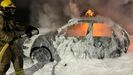 Uno de los coches que se quem con uno de los bomberos