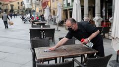 Un camarero desinfecta una mesa de una terraza del centro de Avil�s