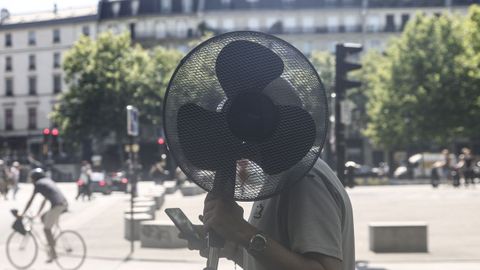 Un hombre lleva un ventilador por las calles de París para hacer frente al calor