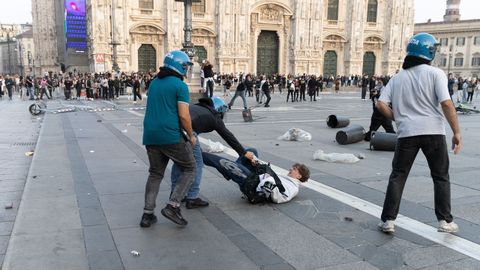 Un polic&iacute;a arrastra a un manifestante en la plaza del Duomo de Mil&aacute;n