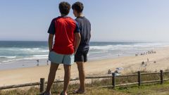 Dos j�venes contemplan la playa de Razo, en julio.