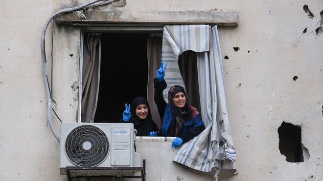 Dos mujeres gesticulan desde un edificio atacado por Israel en Beirut