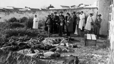 EN EL CEMENTERIO. Autoridades, mdicos y periodistas observan la escena en el cementerio de Casas Viejas, que presentaba un aspecto dantesco con los cuerpos inertes de los vecinos muertos tras el asedio, asalto e incendio de la choza en que viva el Seisdedos, lder de la revuelta anarcosindicalista. Varios agentes vigilan el lugar en que los mdicos efectuarn las autopsias, para lo que se dispuso una rudimentaria mesa de diseccin realizada con dos tablones apoyados sobre toscos cajones de madera