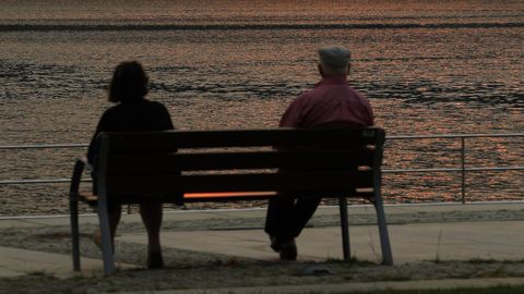 Una pareja de personas mayores sentadas frente al mar