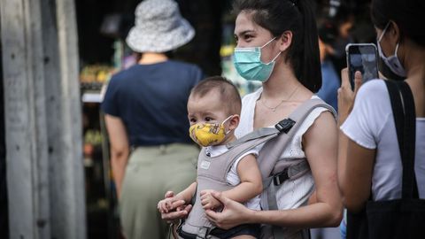 En Tailandia, una madre y su hijo, ambos con mascarilla, acuden a un mercado