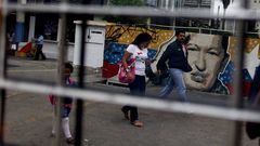 Varias personas caminan frente a un mural con el rostro del presidente Hugo Ch�vez, en el centro de Caracas