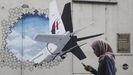 Una mujer pasea frente a un mural sobre el vuelo MH370 de Malaysia Airlines en Shah Alam, a las afueras de Kuala Lumpur