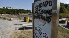 El cartel de la playa de Seiramar, en Covas, donde se recuerdan las normas que fija la ordenanza ha sido objeto de vandalismo