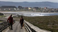 Personas pasean en la senda litoral entre Foz y Barreiros, aprovechando el clima