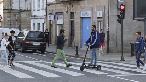 Un usuario de patinete elctrico cruzando la carretera por un paso de peatones, espacio por el cual no puede circular.