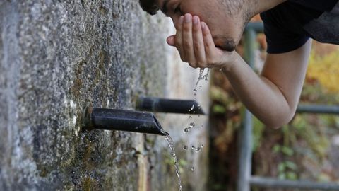 Una persona bebiendo agua en una fuente, en imagen de archivo