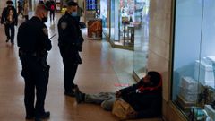 Unos agentes se dirigen a un sintecho en el metro de Nueva York