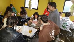 Varios jvenes jugando al tute en un torneo organizado por los estudiantes de tercer curso de Xornalismo y Comunicacin Audiovisual. Juegan por parejas y el premio para los ganadores es una botella de licor caf.