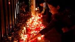 Una mujer coloca una vela en el monumento Love durante una vigilia silenciosa a la luz de las velas para protestar contra el asesinato de la periodista