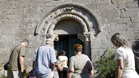 Un grupo de visitantes ante la entrada de la iglesia romnica de San Miguel de Eir, en el municipio de Pantn