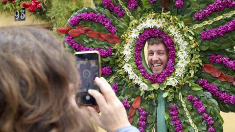 Una persona posa en una de las estructuras florales de las Festas dos Maios de Canido.