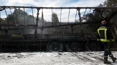 Un bombero pasa delante del cami�n calcinado, en el arcen de la autopista Y.Un bombero pasa delante del cami�n calcinado, en el arcen de la autopista Y