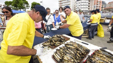 Dos de los encargados repart�an sardinas a vecinos y visitantes que se acercaban tras hacer una larga cola.