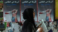 Una mujer camina frente a carteles contra Estados Unidos e Israel en una calle de Beirut