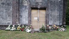 Ramos de flores depositados en el exterior de la iglesia, tras un entierro reciente, en protesta por la negativa del cura a que los dejen dentro