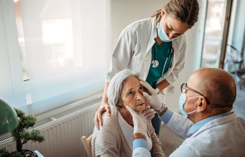 Dos sanitarios examinan la vista a una mujer mayor