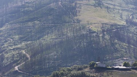 La iglesia de la localidad de Vilamor frente a un monte quemado en julio del 2022