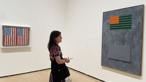 Espectadora entre dos de los lienzos de la serie &laquo;Flags&raquo; [Banderas], realizados, de izquierda a derecha, en 1987 y 1965.
