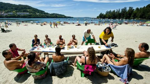 LOS PINARES. Cabana. En Los Pinares no es que comas a pie de playa (que también, en su terraza), es que puedes comer con los pies enterrados en la arena. Dos tablas de surf hacen las veces de mesa en la que poder degustar las especialidades de este chiringuito, elegido en 2022 por Forbes como el mejor de Galicia. Entre ellas, la paella cabanesa (la única de Galicia registrada en la Oficina Española de Patentes y Marcas) o el Vía Láctea, un postre cuya receta ha sido creada por Inteligencia Artificial.